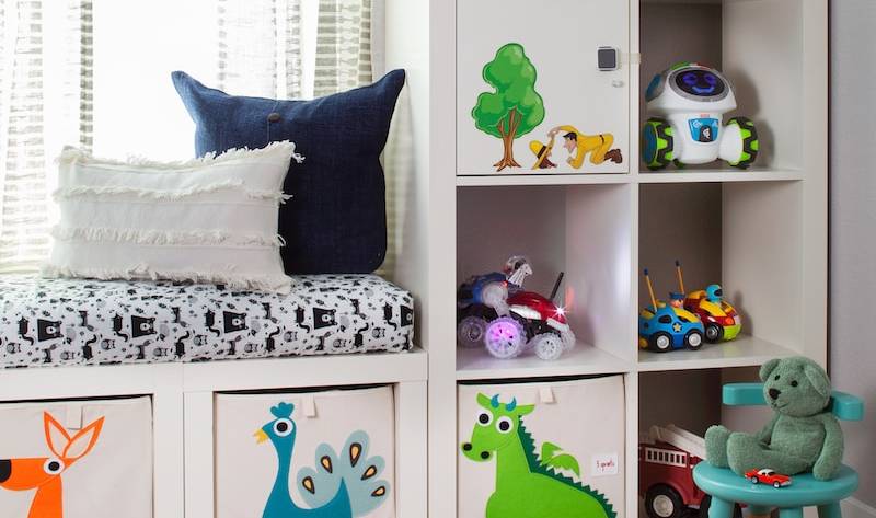 Children's room with toys, storage shelves, robot decor, and playful cushions in a cosy space