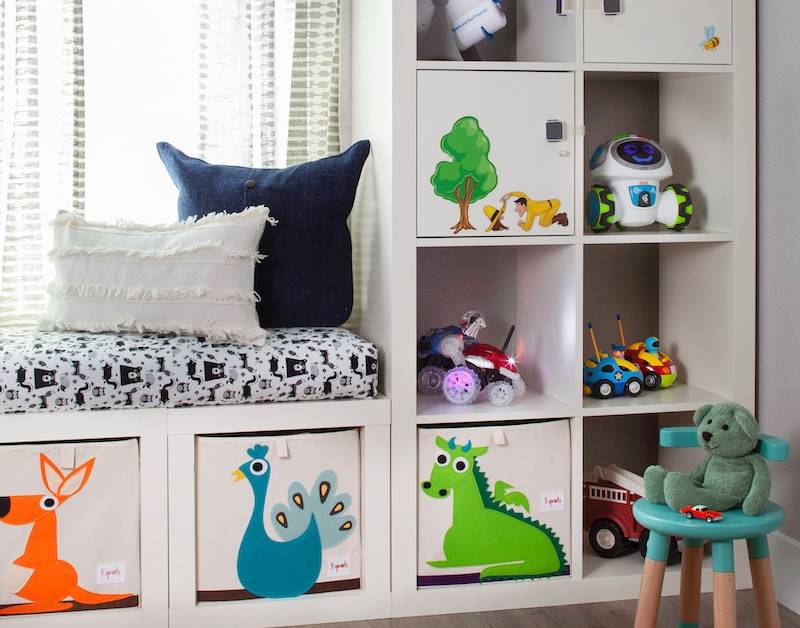 Children's room with toys, storage shelves, robot decor, and playful cushions in a cosy space