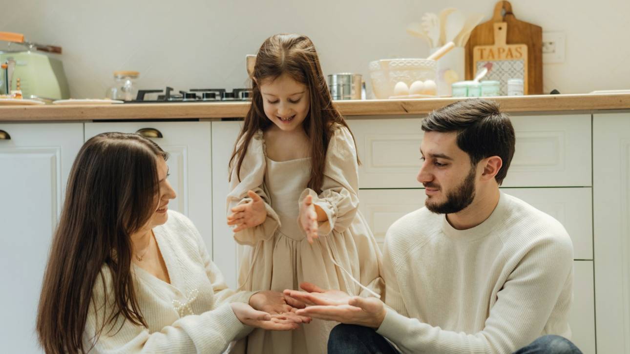 Family playing together in a cosy kitchen, wearing matching cream-coloured outfits and enjoying a joyful moment