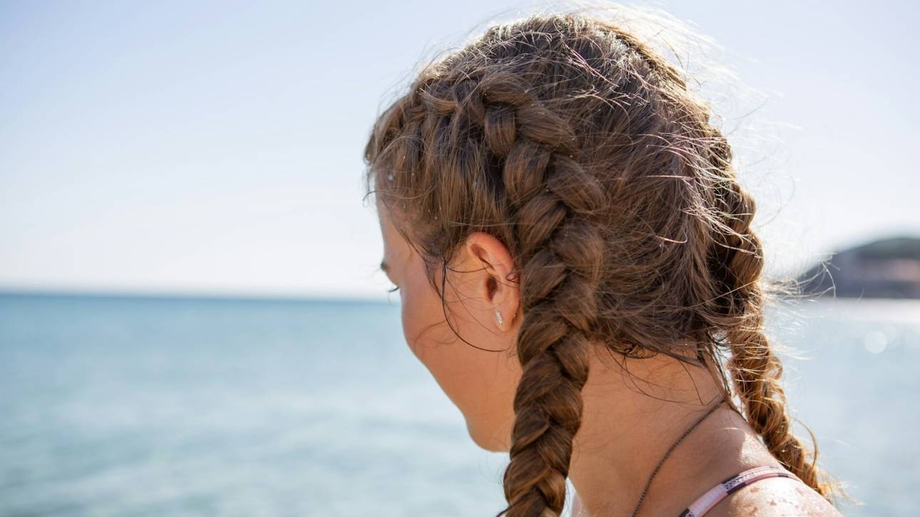 Young woman with braided hair enjoying a sunny beach view near the ocean